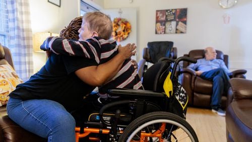 A caregiver hugs resident Jeffrey Clarke in a group home for people with disabilities in Tucker in November 2022.  (Arvin Temkar/AJC 2022)