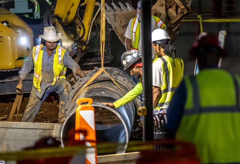 Workers lowered a large pipe at 11th and West Peachtree Street on Tuesday as part of an effort to fix Atlanta's water problem.