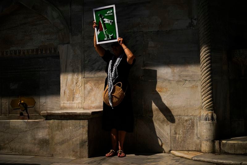 A woman holds up a poster that reads: "The Land" during a protest in memory of Aysenur Ezgi Eygi, a 26 year-old Turkish-American activist killed by the Israeli military, in Istanbul, Turkey, Saturday, Sept. 14, 2024. (AP Photo/Francisco Seco)