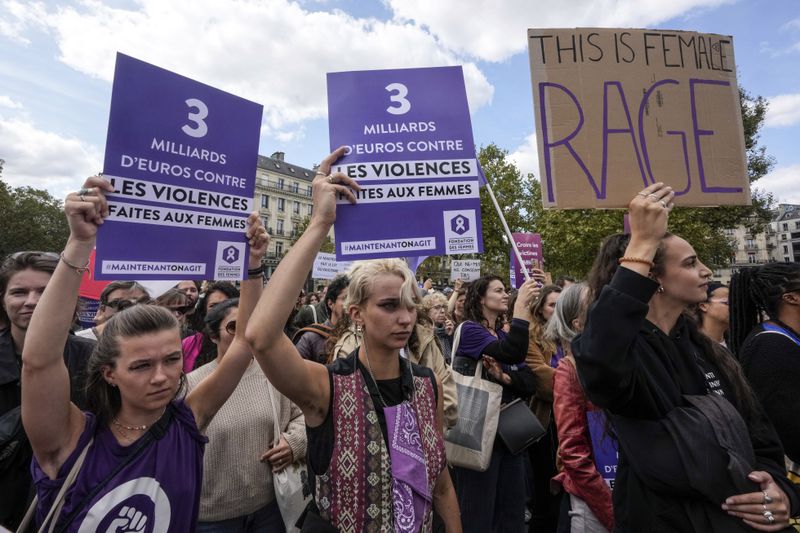 People take part in a gathering in support of 71-year-old Gisele Pelicot who was allegedly drugged by her ex-husband and raped by dozens of men while unconscious, Saturday, Sept. 14, 2024 in Paris. Placards left read, "3 billion euros to combat violence against women." (AP Photo/Michel Euler)