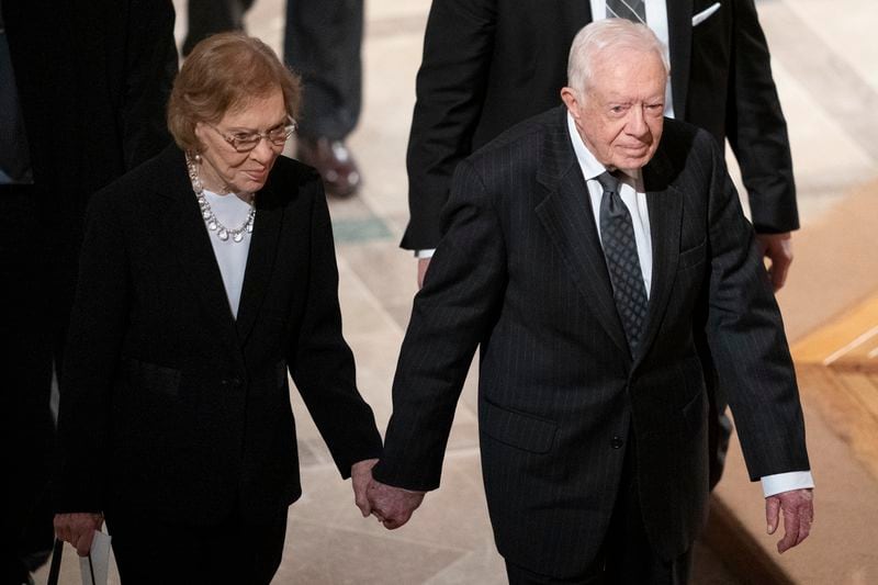 FILE - Former President Jimmy Carter, right, and his wife, former first lady Rosalynn Carter, hold hands as they walk from a state funeral for former President George H.W. Bush at the National Cathedral, Dec. 5, 2018, in Washington. (AP Photo/Carolyn Kaster, File)