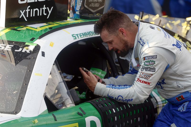 Driver Ricky Stenhouse Jr. talks with his wife and son on the phone as he celebrates in Victory Lane after a NASCAR Cup Series auto race at Talladega Superspeedway, Sunday, Oct. 6, 2024, in Talladega, Ala. (AP Photo/ Butch Dill)