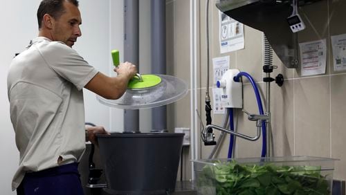 Pierre Bigot, a local sous chef, dries spinach in the kitchen of the United States Olympic and Paralympic Committee's High Performance Center's kitchen on Saturday, Aug. 31, 2024. The USOPC brought in staff from Colorado and also hired local chefs to work in the kitchen. (AP Photo/Nathalee Simoneau)