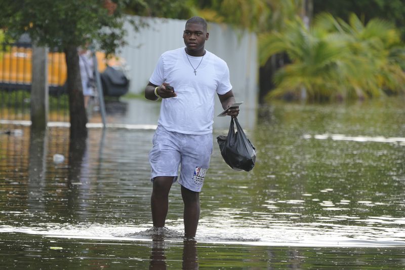 A man walks on a flooded street on his way to work, Thursday, June 13, 2024, in North Miami, Fla. A tropical disturbance has brought a rare flash flood emergency to much of southern Florida. Floridians prepared to weather more heavy rainfall on Thursday and Friday. (AP Photo/Marta Lavandier)
