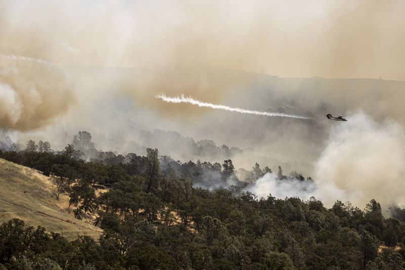 A Cal Fire OV-10 air tactical aircraft releases a puff of smoke while guiding a fire retardant drop during the Thompson Fire, in Oroville, Calif., Wednesday, July 3, 2024. (Stephen Lam/San Francisco Chronicle via AP)
