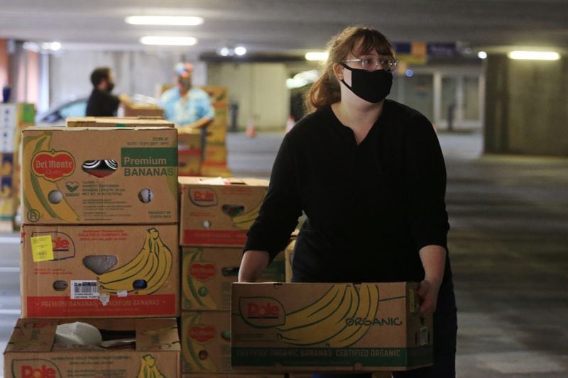 Emily Schubert, volunteer from Rhino Staging, loads food boxes into cars during the Musically Fed food drive Oct. 29 at the Infinite Energy Center in Duluth. CHRISTINA MATACOTTA FOR THE AJC
