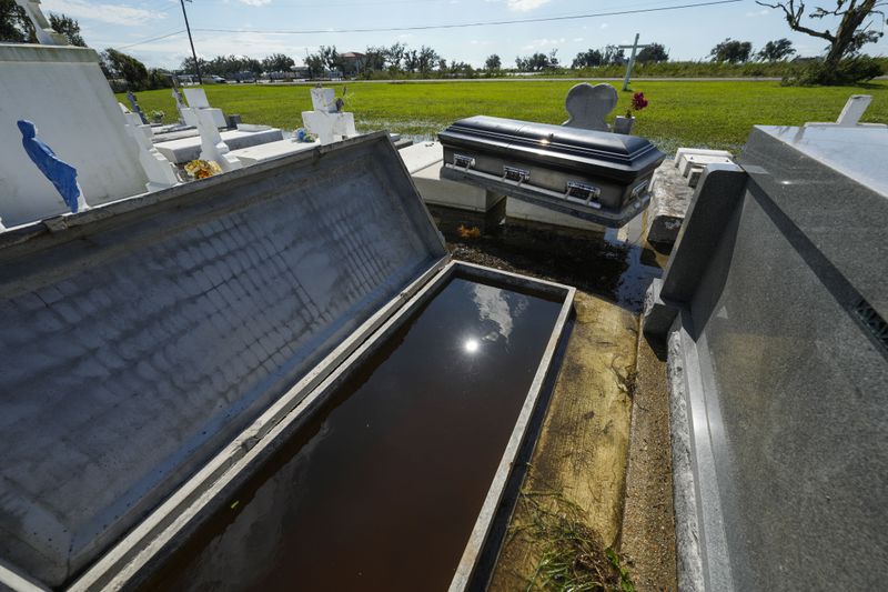 A casket sits on an adjacent tomb after floating out of its tomb at Holy Family Cemetery No. 2, Thursday, Sept. 12, 2024, Dulac, La., following floodinig from Hurricane Francine. (AP Photo/Gerald Herbert)