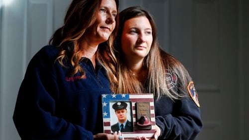 Pamela Yarosz and her daughter Capri are shown with a photo of New York firefighter Christopher Michael Mozzillo Saturday, Sept. 7, 2024, in Freehold, N.J.. Mozzillo, who died in the 9/11 attacks, was Pamela's brother. (AP Photo/Noah K. Murray)