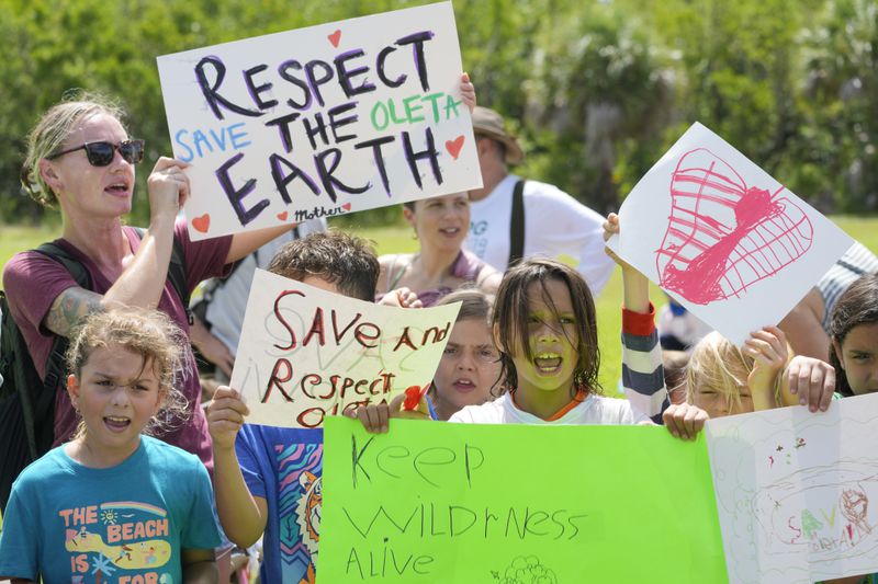 Protesters chant against Gov. Ron DeSantis' plan to develop state parks with business ventures such as golf courses, pickleball courts and large hotels, during a demonstration at Oleta River State Park, Tuesday, Aug. 27, 2024, in North Miami Beach, Fla. (AP Photo/Wilfredo Lee)