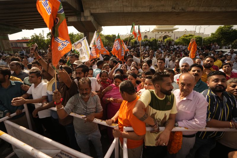 Bharatiya Janata Party (BJP) supporters hold party flags and wait outside a counting center in Jammu, India, Tuesday, Oct. 8, 2024. (AP Photo/Channi Anand)