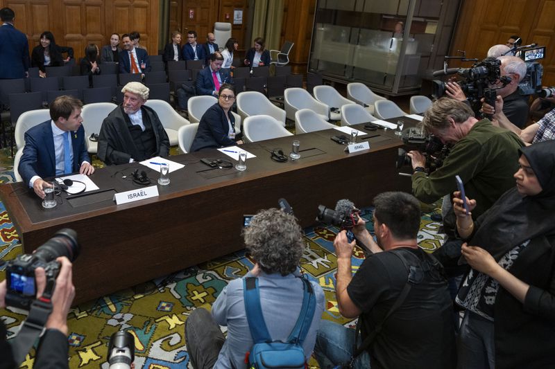 Journalists take images of Israel's legal team, with Yaron Wax, Malcolm Shaw and Avigail Frisch Ben Avraham, from left, before Judges enter the International Court of Justice, or World Court, in The Hague, Netherlands, Friday, May 24, 2024, where the top United Nations court ordered Israel on Friday to immediately halt its military operations in the southern Gaza city of Rafah. (AP Photo/Peter Dejong)