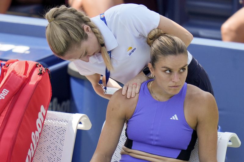 Maria Sakkari, of Greece, reacts as a trainer works on her shoulder between games against Wang Yafan, of China, during the first round of the U.S. Open tennis championships, Monday, Aug. 26, 2024, in New York. (AP Photo/Seth Wenig)