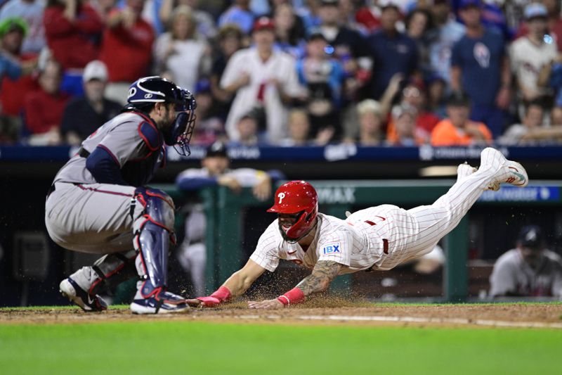 Philadelphia Phillies' Weston Wilson, right, dives to score past Atlanta Braves' Travis d'Arnaud, left, during the seventh inning of a baseball game, Saturday, Aug. 31, 2024, in Philadelphia. (AP Photo/Derik Hamilton)