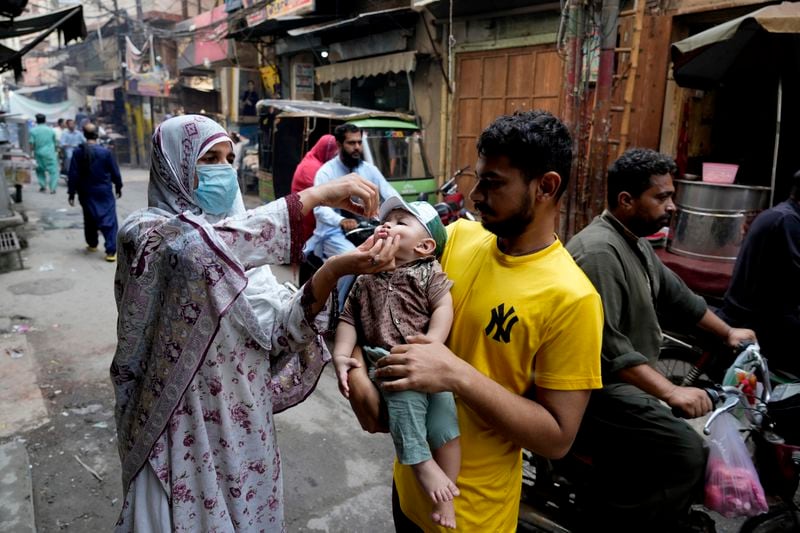 A health worker administers a polio vaccine to a child in a market in downtown area of Lahore, Pakistan, Monday, Sept. 9, 2024. (AP Photo/K.M. Chaudary)