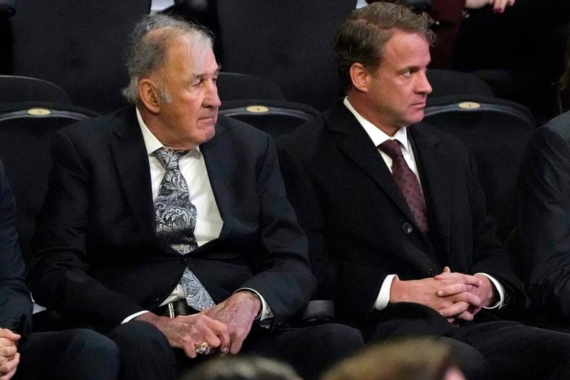 FILE - Mississippi head football coach Lane Kiffin, right and his father, Monte Kiffin, a player personnel analyst on his staff, listen during a memorial service fo rthe late Mississippi State football coach Mike Leachat Humphrey Coliseum on the university's campus in Starkville, Miss., Tuesday, Dec. 20, 2022. Monte Kiffin, a long-time NFL assistant coach whose Tampa Bay Buccaneers defenses routinely ranked among the league’s best, died Thursday, July 11, 2024. He was 84. (AP Photo/Rogelio V. Solis, File)