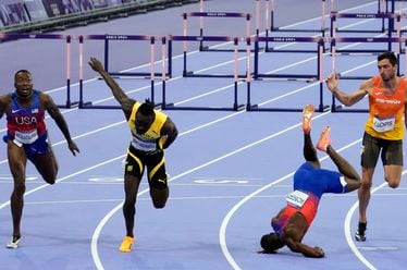 Grant Holloway, left, of the United States, wins the men's 110-meters hurdles final as teammate Daniel Roberts, takes a tumble at the line, at the 2024 Summer Olympics, Thursday, Aug. 8, 2024, in Saint-Denis, France. (AP Photo/Martin Meissner)