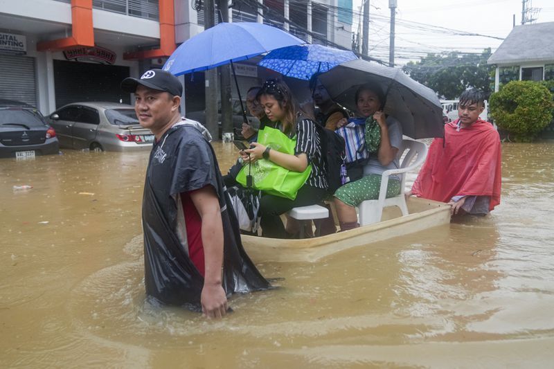 Residents ride on an improvised float through flood waters caused by heavy rains from Tropical Storm Yagi, locally called Enteng, as they return to their homes on Monday, Sept. 2, 2024, in Cainta, Rizal province, Philippines. (AP Photo/Aaron Favila)