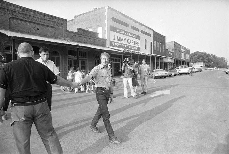 Democratic presidential nominee Jimmy Carter shakes hands with tourists as he takes an early morning walk down the main street of Plains, Ga., on July 30, 1976. (Peter Bregg/AP)