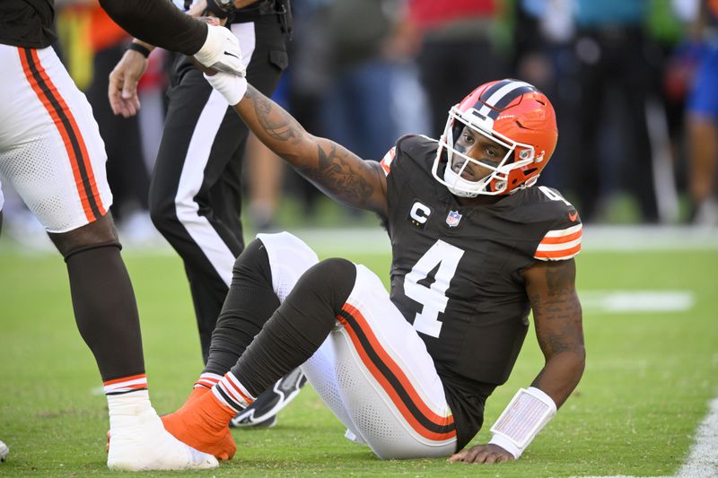 Cleveland Browns quarterback Deshaun Watson (4) is helped up by James Hudson III, left, after Watson threw an incomplete pass in the second half of an NFL football game against the Dallas Cowboys in Cleveland, Sunday, Sept. 8, 2024. (AP Photo/David Richard)