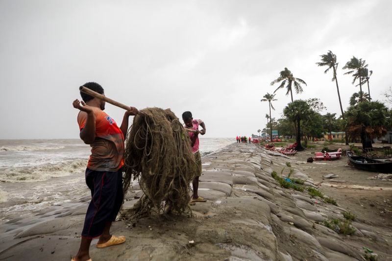 Men move fishing nets as water flows on to the Kuakata beach on the coast of Bay of Bengal caused by the advancing Cyclone Remal in Barisal, Bangladesh, Sunday, May 26, 2024. (AP Photo/Abdul Goni)