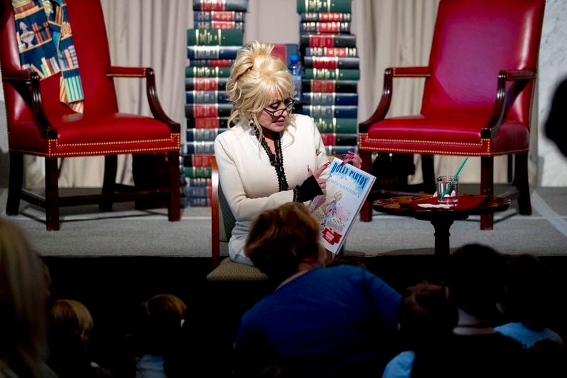 Singer-songwriter Dolly Parton reads her book "Coat of Many Colors" to children during an an event where her organization Imagination Library donates it as the 100 millionth book to the Library of Congress collection, Tuesday, Feb. 27, 2018 in Washington. The Library of Congress and Imagination Library also announce a story time for children on the last Friday of each month in the Great Hall of the Thomas Jefferson Building from March through August. (AP Photo/Andrew Harnik)