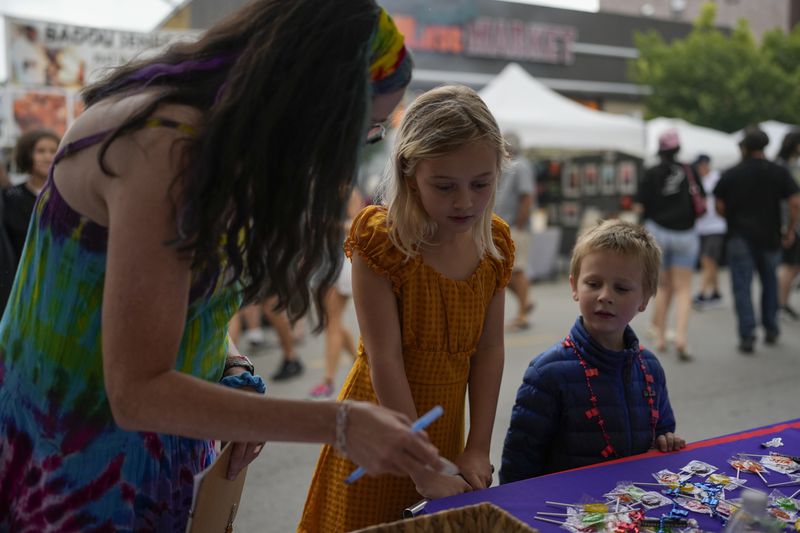 Illinois Rep. Kelly Cassidy, left, talks with visitors to the Glenwood Avenue Arts Festival, Quinn Kalman, 10, center, and Harrison Kalman, 6, left, Monday, Aug. 26, 2024, in Chicago. (AP Photo/Erin Hooley)