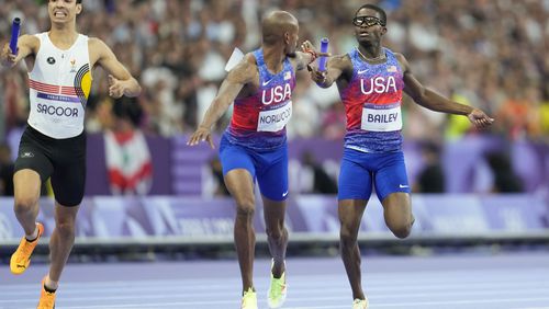 Christopher Bailey, of the United States, hands the baton to teammate Vernon Norwood, in the men's 4 x 400 meters relay final at the 2024 Summer Olympics, Saturday, Aug. 10, 2024, in Saint-Denis, France. (AP Photo/Ashley Landis)