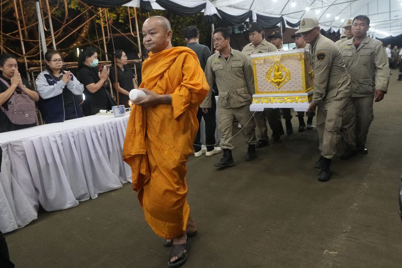 A monk leads a coffin procession containing the body of a victim of a bus fire as they arrive at Wat Khao Phraya Sangkharam School Lan Sak , Uthai Thani province, Thailand, Thursday, Oct. 3, 2024. (AP Photo/Sakchai Lalit)