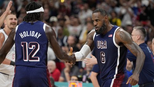 LeBron James, right, of the United States, celebrates with Jrue Holiday, of the United States, after scoring in a men's basketball game against Serbia at the 2024 Summer Olympics, Sunday, July 28, 2024, in Villeneuve-d'Ascq, France. (AP Photo/Michael Conroy)