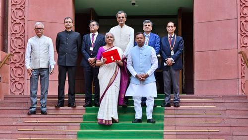 Indian Finance Minister Nirmala Sitharaman, carrying a red pouch containing budget documents, poses for a photograph with colleagues as she arrives to present the federal budget in the Parliament in New Delhi, India, Tuesday, July 23, 2024. (AP Photo)