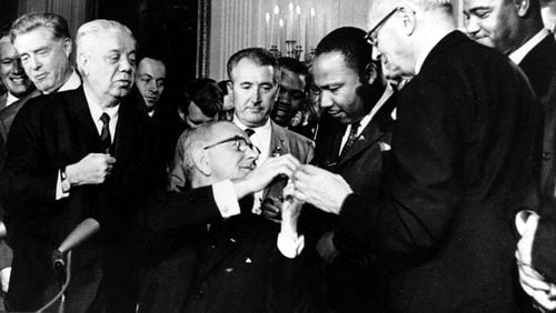 Tuesday marked 60 years since U.S. President Lyndon B. Johnson signed into law the Civil Rights Act of 1964. At the signing ceremony, Johnson reaches to shake hands with the Martin Luther King Jr. after presenting the civil rights leader with one of the 72 pens used to sign the measure. (AP Photo)