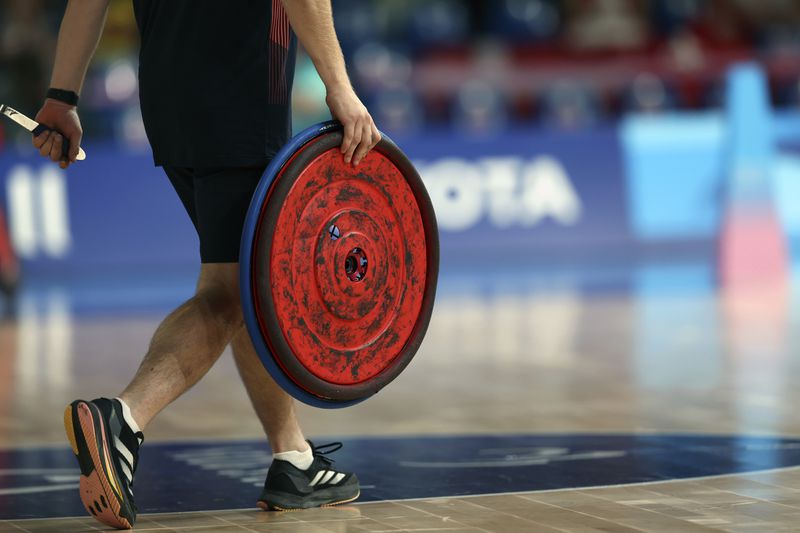 A Great Britain team member walks on to the court to change a wheel during the Great Britain vs Denmark wheelchair rugby preliminary match at the Paralympic Games in Paris on Friday, Aug. 30, 2024. Great Britain won the game 55-53. Team technicians can handle some repairs but others can be handled by on-site technicians from Ottobock. (AP Photo/Avni Trivedi)