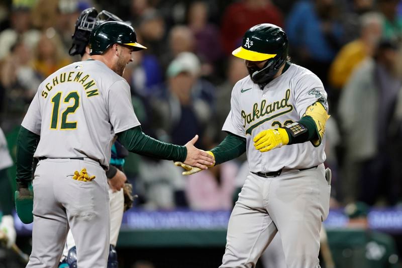 Oakland Athletics' Shea Langeliers, right, is greeted by Max Schuemann at home after hitting a three-run home run on a pitch from Seattle Mariners pitcher Collin Snider during the ninth inning in a baseball game, Saturday, Sept. 28, 2024, in Seattle. (AP Photo/John Froschauer)