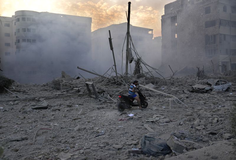 A man rides his scooter through debris of destroyed buildings hit by Israeli airstrikes in Dahiyeh, Beirut, Lebanon, Sunday, Oct. 6, 2024. (AP Photo/Hussein Malla)