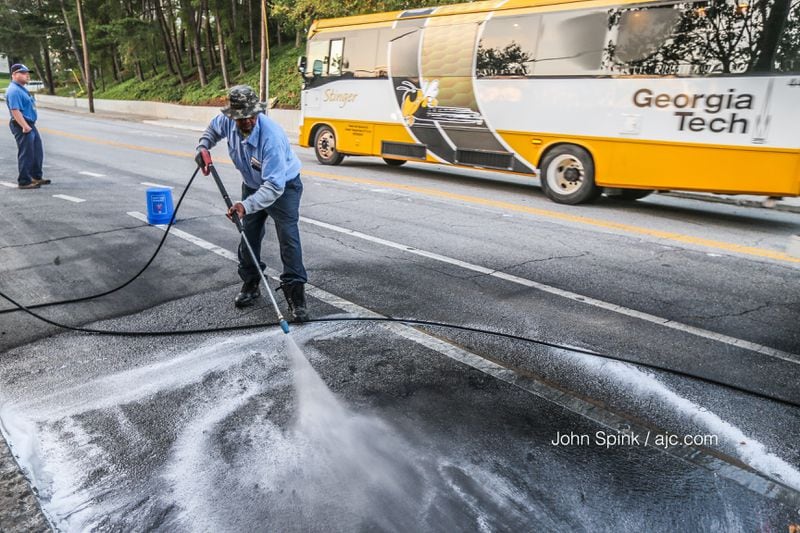 Early Tuesday, a Georgia Tech worker pressure washed the spot where a police car burned during a night of violent protests on the campus. JOHN SPINK / JSPINK@AJC.COM