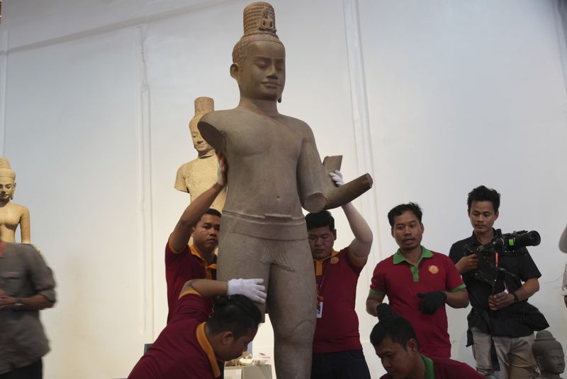 Museum staff members place an artifact as it returned from U.S to Cambodia, before an official ceremony at the Cambodian National Museum in Phnom Penh Cambodia, Thursday, July 4, 2024. Cambodia on Thursday officially organized a welcome ceremony for the arrival of more than a dozen rare Angkor era sculptures from New York's Metropolitan Museum of Art that were tied to an art dealer and collector accused of running a huge antiquities trafficking network out of Southeast Asia. (AP Photo/Heng Sinith)