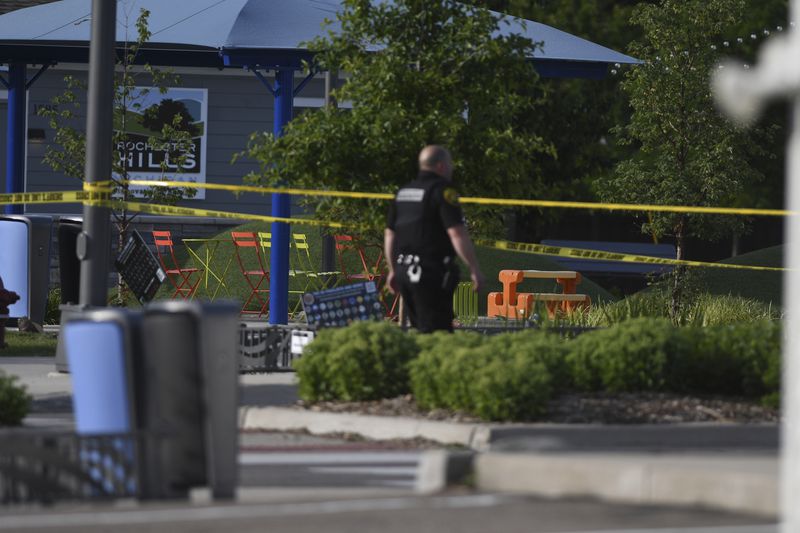 A police officer walks across the plaza of the Brooklands Plaza Splash Pad in Rochester Hills, Mich., where police say there was an active shooter Saturday, June 15, 2024. (Daniel Mears/Detroit News via AP)