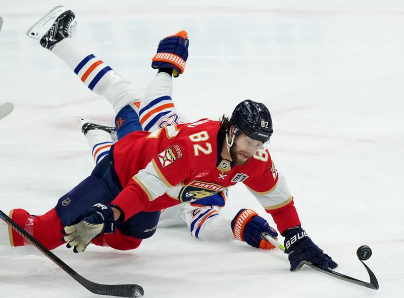 Florida Panthers forward Kevin Stenlund (82) takes Edmonton Oilers forward Leon Draisaitl, back, to the ice while defending without his stick during the second period of Game 7 of the NHL hockey Stanley Cup Final in Sunrise, Fla., Monday, June 24, 2024. (Nathan Denette/The Canadian Press via AP)