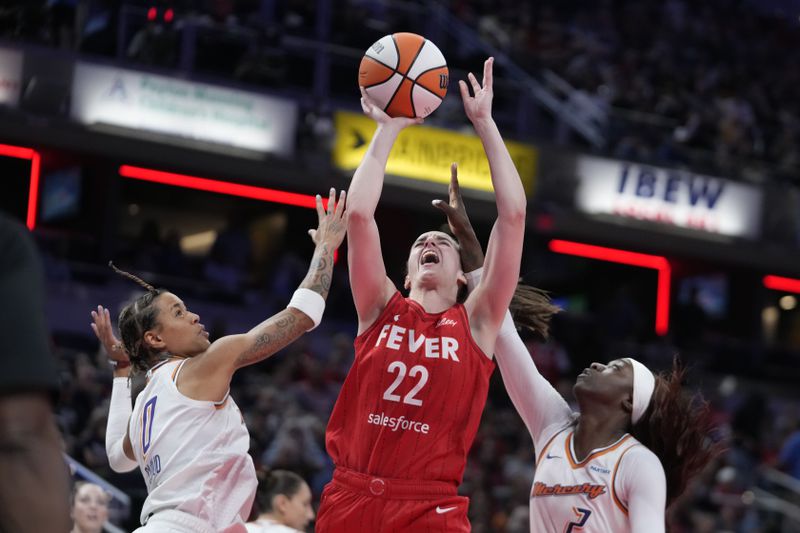 Indiana Fever guard Caitlin Clark (22) shoots against Phoenix Mercury's Natasha Cloud (0) and Kahleah Copper (2) during the second half of a WNBA basketball game, Friday, Aug. 16, 2024, in Indianapolis. (AP Photo/Darron Cummings)