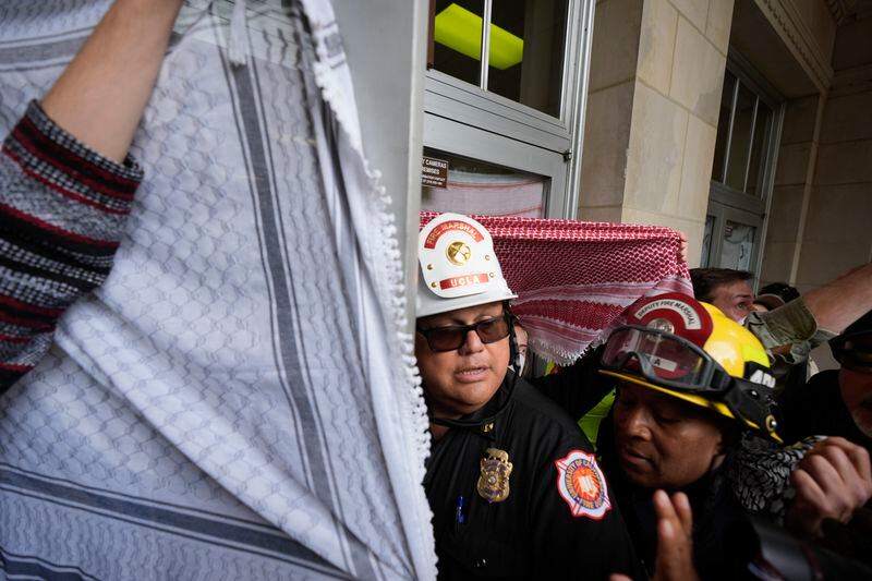 The Fire Marshal pushes his way through Pro-Palestinian demonstrators at Dodd Hall on the UCLA campus on Thursday, May 23, 2024, in Los Angeles. (AP Photo/Ryan Sun)