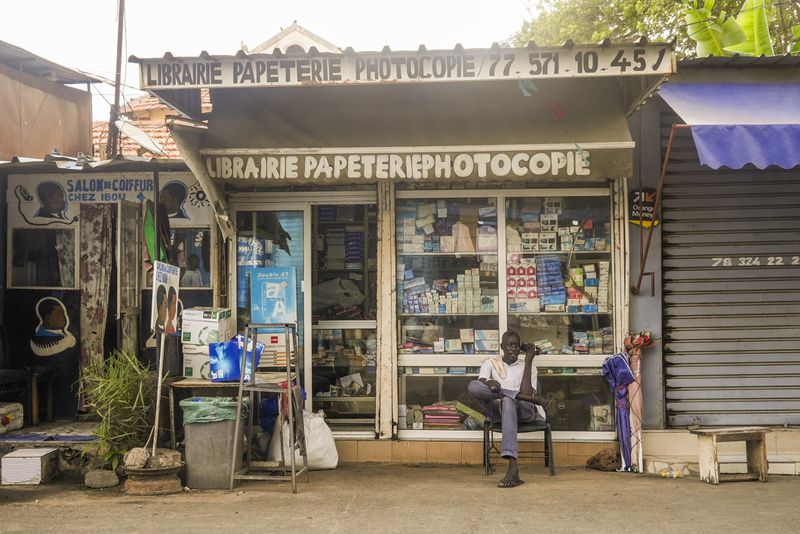 A man sits outside a stationary store with French signs in Dakar, Senegal, Thursday, Oct. 3, 2024. (AP Photo/Annie Risemberg)