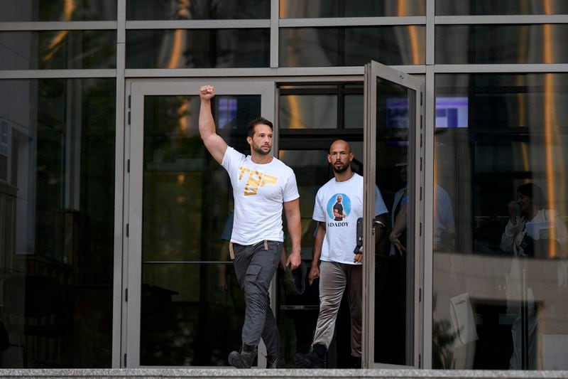 Andrew Tate, right, and his brother Tristan, left, exit the Bucharest Tribunal after being placed under house arrest, in Bucharest, Romania, Thursday, Aug. 22, 2024. A court in Romania's capital on Thursday placed the divisive internet influencer Andrew Tate under house arrest for 30 days, as prosecutors investigate a sprawling new case that involves allegations of human trafficking of minors and sex with a minor. (AP Photo/Alexandru Dobre)