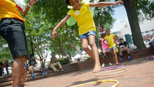 Nia Caudle (center) jumps into the center of a hoop as she plays games during the Cobb NAACP Juneteenth Celebration in Marietta Square. JONATHAN PHILLIPS / SPECIAL