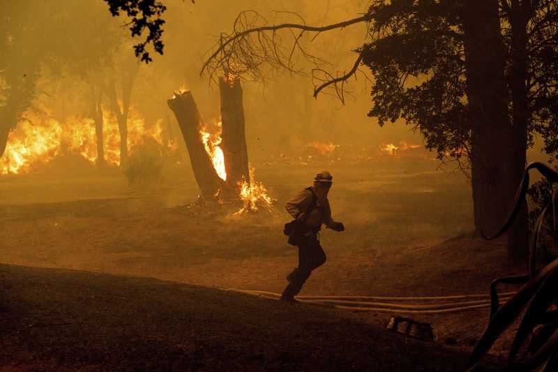 A firefighter runs while battling the Thompson Fire burning in Oroville, Calif., Tuesday, July 2, 2024. An extended heatwave blanketing Northern California has resulted in red flag fire warnings and power shutoffs. (AP Photo/Noah Berger)