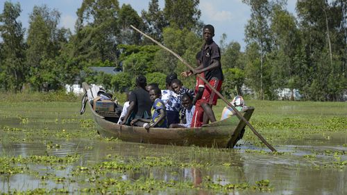 FILE - A family uses a canoe after fleeing floodwaters that wreaked havoc in Ombaka Village, Kisumu, Kenya, April 17, 2024. The impact of the calamitous rains that struck East Africa from March to May was intensified by a mix of climate change and rapid growth of urban areas, an international team of climate scientists said in a study. (AP Photo/Brian Ongoro, File)