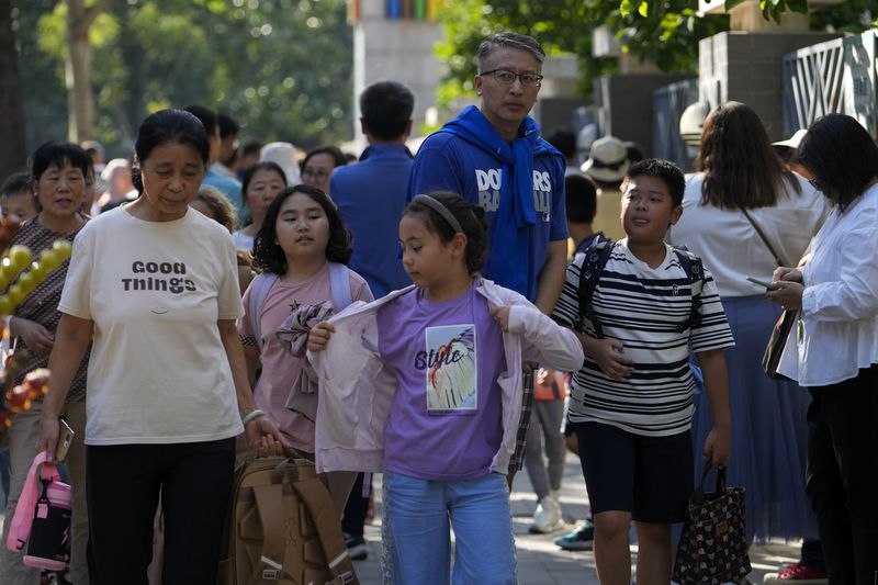 People pick up their children after school in Beijing, Friday, Sept. 13, 2024. (AP Photo/Andy Wong)