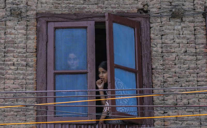 People watch from a window during a road show of Peoples Democratic Party (PDP) candidate Arif Laigroo, in Srinagar, Indian-controlled Kashmir Sunday, Sept. 15, 2024. (AP Photo/Mukhtar Khan, File)