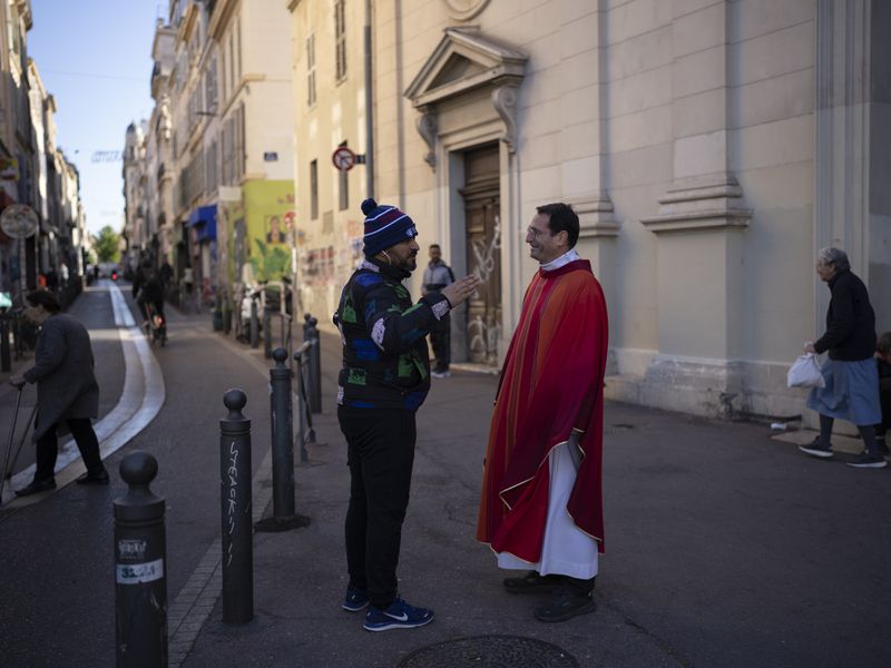 Father Alexis Leproux speaks with a passersby after morning Mass at the Notre-Dame du Mont church in Marseille, southern France, Thursday, April 25, 2024. (AP Photo/Daniel Cole)