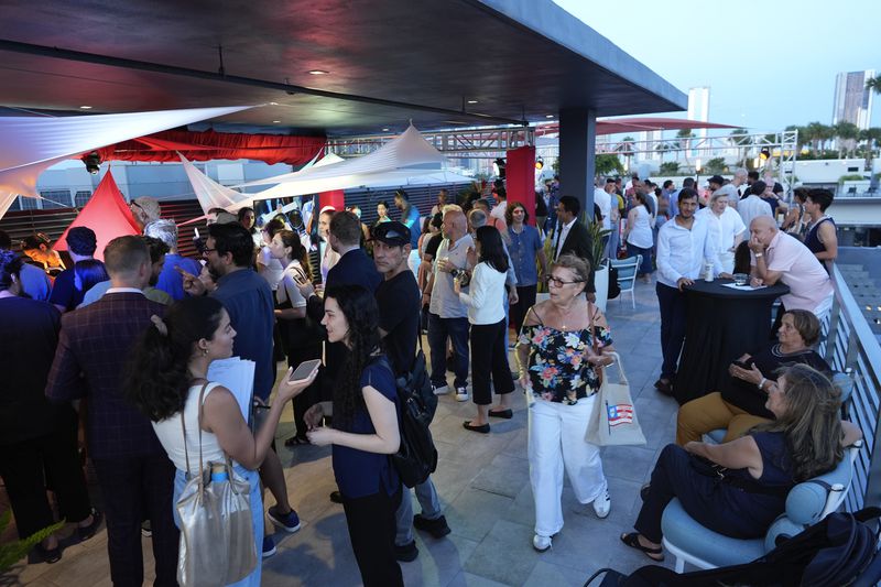 People mingle on a rooftop terrace during a pop-up tasting event for "lab-grown" meat produced by California-based Upside Foods, Thursday, June 27, 2024, in Miami. As Florida's ban on lab-grown meat is set to go into effect next week, one manufacturer hosted a tasting party, serving up cultivated chicken tostadas to dozens of attendees on a rooftop in Miami's Wynwood neighborhood. (AP Photo/Rebecca Blackwell)