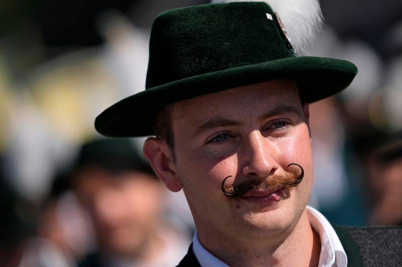 A visitor in traditional Bavarian clothes and a moustache is seen at the start of the 189th 'Oktoberfest' beer festival in Munich, Germany, Saturday, Sept. 21, 2024. (AP Photo/Matthias Schrader)